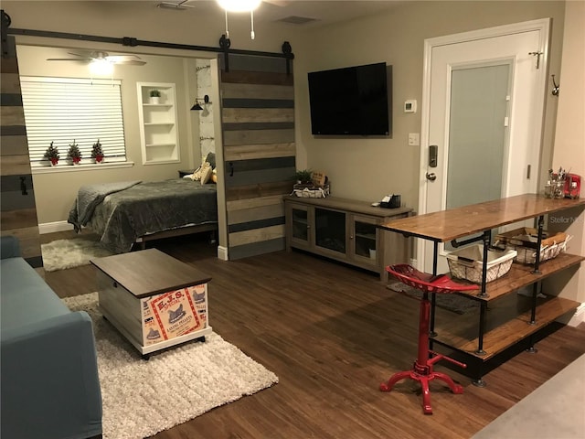 bedroom with a barn door, wood finished floors, and baseboards