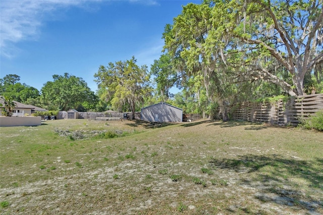 view of yard featuring a shed, an outdoor structure, and fence