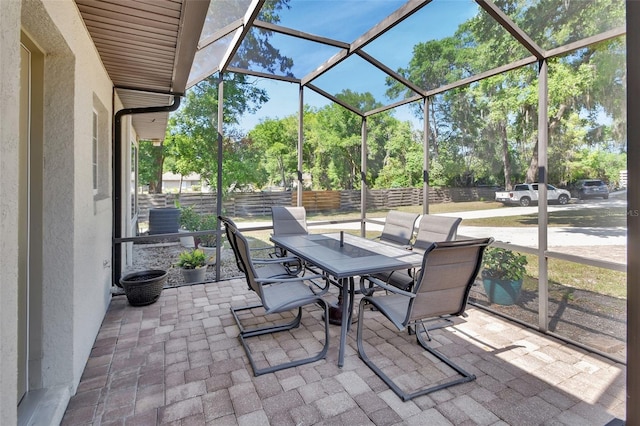 view of patio / terrace with outdoor dining area, fence, central AC, and view of wooded area