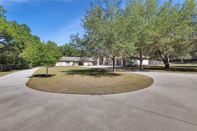 view of community with curved driveway and a lawn