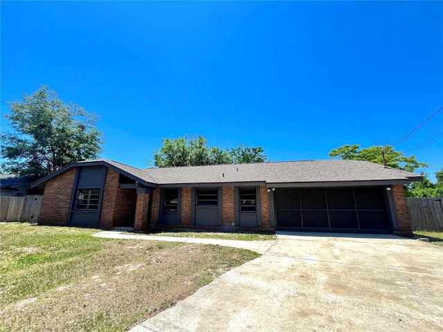 ranch-style house featuring brick siding, fence, driveway, a front lawn, and an attached garage
