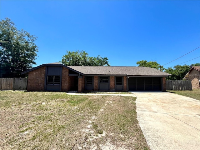 single story home with a front lawn, driveway, brick siding, an attached garage, and fence