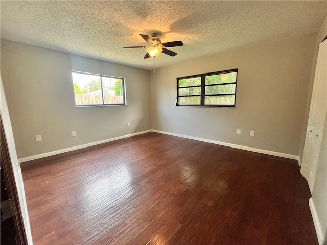 unfurnished room featuring dark wood finished floors, a ceiling fan, a wealth of natural light, and a textured ceiling