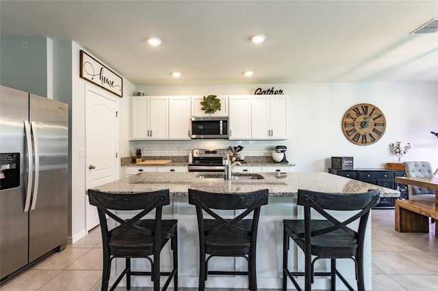 kitchen with light stone countertops, visible vents, appliances with stainless steel finishes, and decorative backsplash