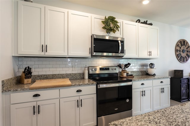 kitchen featuring light stone countertops, decorative backsplash, white cabinets, and appliances with stainless steel finishes
