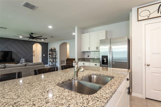 kitchen with white cabinets, arched walkways, a sink, visible vents, and stainless steel fridge with ice dispenser