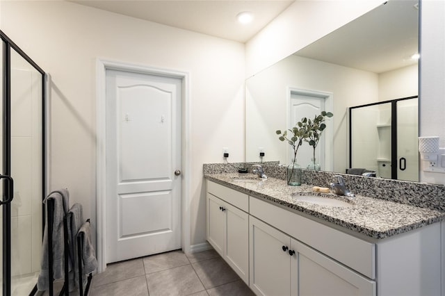 bathroom with tile patterned floors, a sink, double vanity, and a stall shower