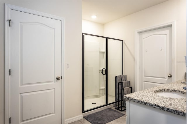 bathroom featuring baseboards, vanity, tile patterned flooring, and a shower stall