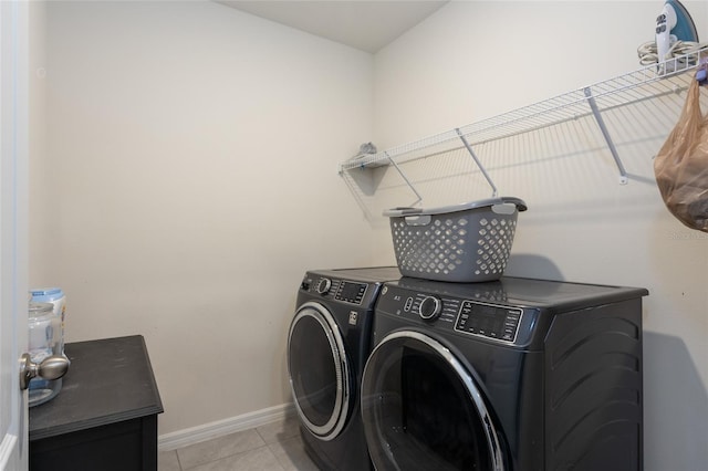 laundry area featuring light tile patterned floors, washing machine and clothes dryer, baseboards, and laundry area