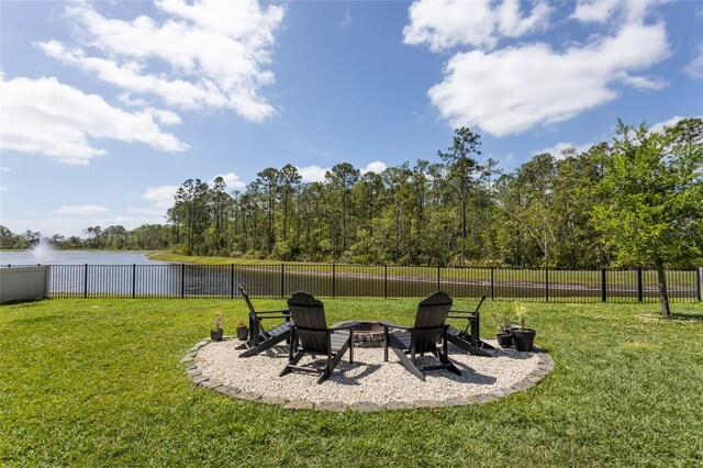 view of yard with a fire pit, fence, and a water view
