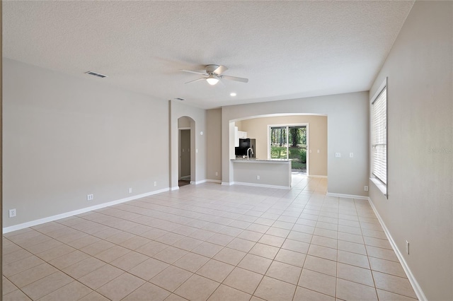417 Victoria Hills Dr, Deland, FL 32724 - empty room with arched walkways, a ceiling fan, a textured ceiling, and light tile patterned floors