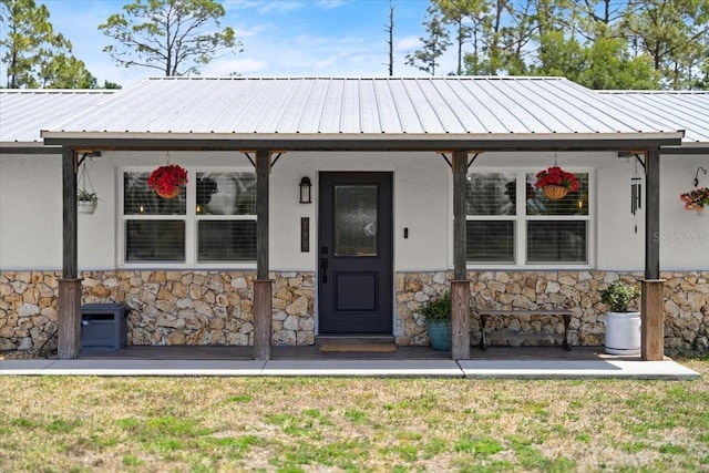 view of front of property with metal roof, stucco siding, a front lawn, and stone siding