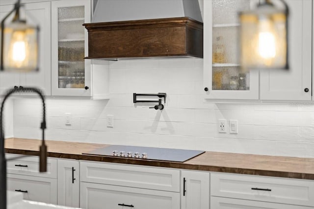 kitchen with black electric cooktop, butcher block counters, and tasteful backsplash