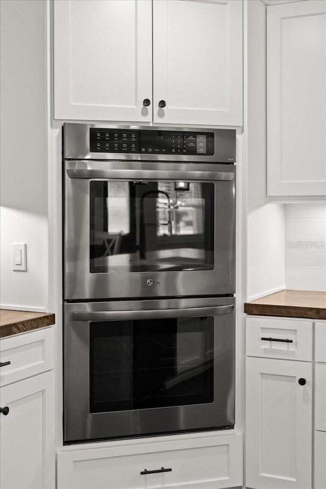 details with white cabinetry, wooden counters, and double oven