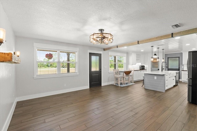 interior space featuring a notable chandelier, light countertops, a textured ceiling, baseboards, and stainless steel appliances