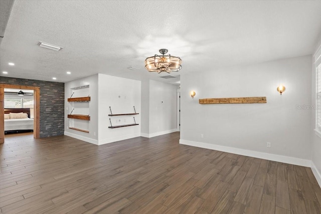 unfurnished living room featuring a textured ceiling, a chandelier, wood finished floors, and baseboards