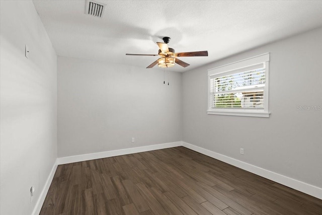 spare room with dark wood-style flooring, baseboards, a ceiling fan, and visible vents