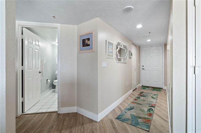 hall featuring baseboards, recessed lighting, and light wood-style flooring