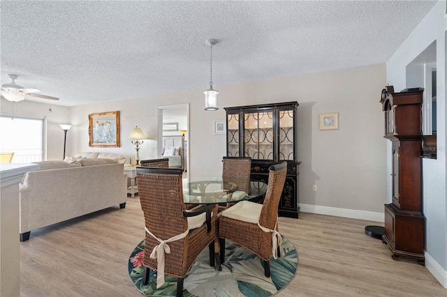 dining area with baseboards, a textured ceiling, ceiling fan, and light wood-style floors