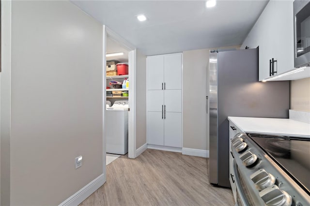 kitchen with light wood-type flooring, baseboards, stainless steel appliances, white cabinetry, and washer and clothes dryer