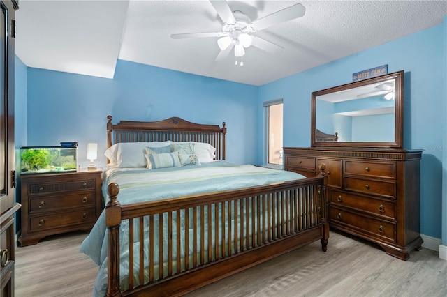 bedroom featuring baseboards, a textured ceiling, ceiling fan, and wood finished floors