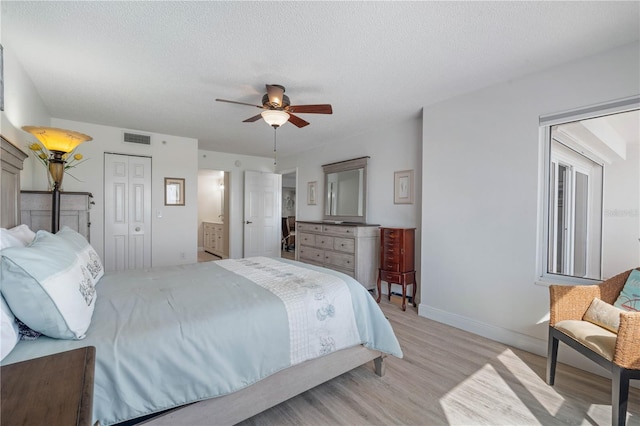 bedroom with baseboards, light wood-type flooring, a textured ceiling, and visible vents