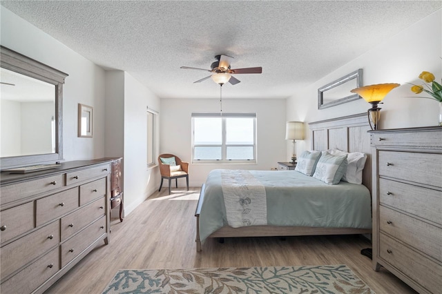 bedroom featuring a textured ceiling, ceiling fan, and light wood finished floors