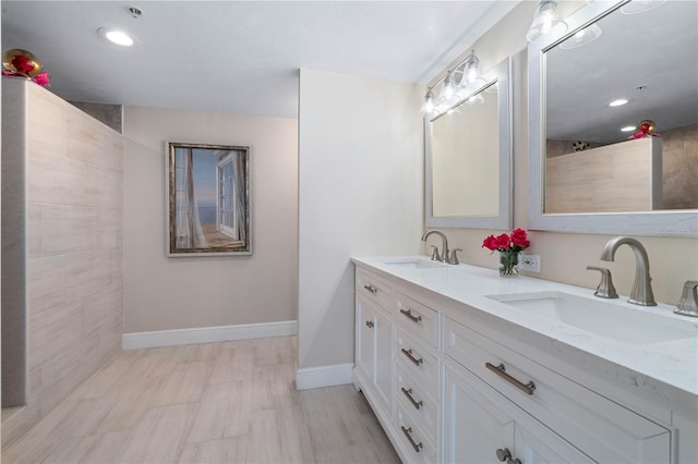 full bath featuring a sink, baseboards, and double vanity