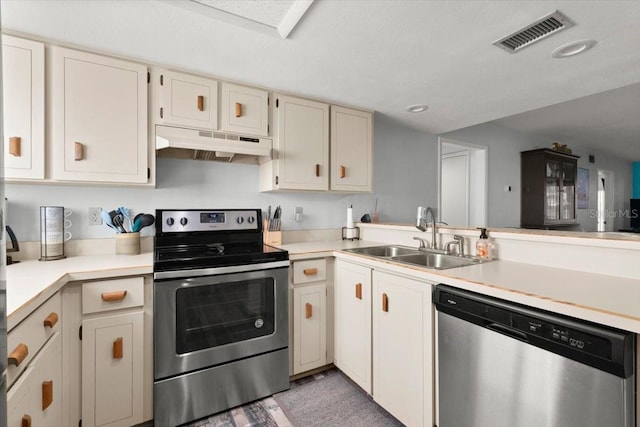 kitchen featuring stainless steel appliances, under cabinet range hood, a sink, visible vents, and a peninsula
