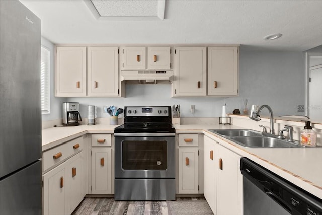 kitchen featuring a sink, stainless steel appliances, light wood-style floors, under cabinet range hood, and light countertops