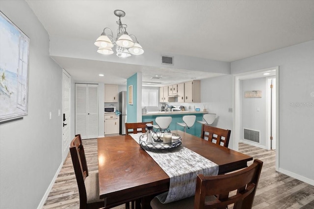 dining area featuring an inviting chandelier, visible vents, light wood-style flooring, and baseboards
