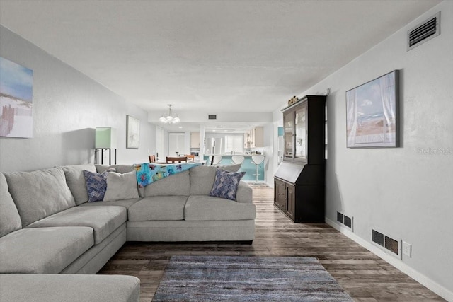 living room featuring an inviting chandelier, dark wood-style flooring, and visible vents