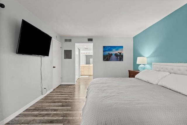 bedroom featuring wood finished floors, visible vents, connected bathroom, and baseboards