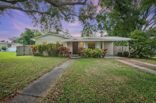single story home with stucco siding, a front lawn, fence, and an attached carport