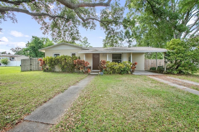 ranch-style house with fence, a front yard, stucco siding, driveway, and a carport