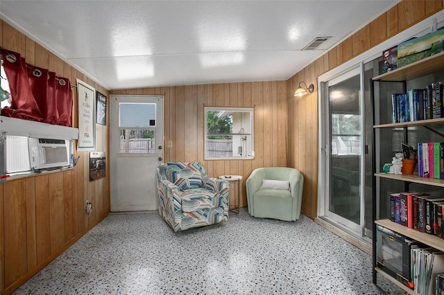 sitting room featuring wooden walls, cooling unit, and visible vents