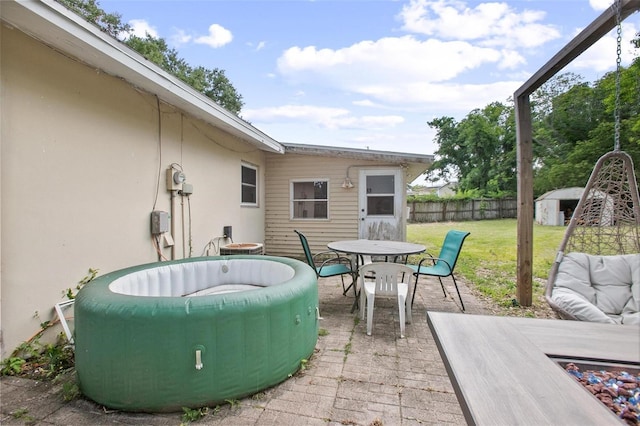 view of patio featuring a storage unit, fence, an outbuilding, and outdoor dining space