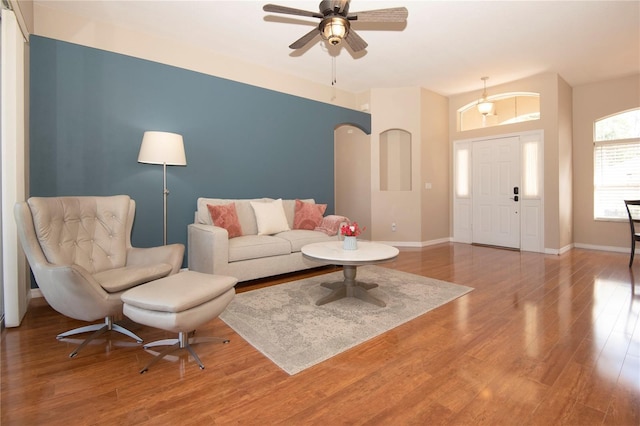 living area with baseboards, wood finished floors, and ceiling fan