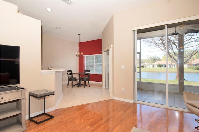 interior space with recessed lighting, light wood-style floors, a notable chandelier, a water view, and baseboards
