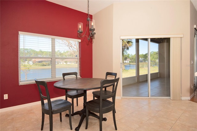 dining area with light tile patterned floors, a notable chandelier, high vaulted ceiling, and baseboards