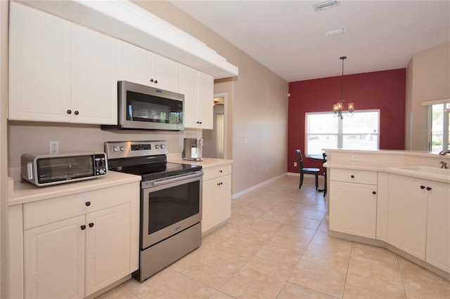 kitchen featuring a toaster, stainless steel appliances, light countertops, a sink, and a notable chandelier