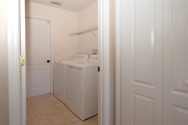 clothes washing area featuring light tile patterned floors, visible vents, washer and dryer, and laundry area