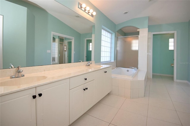 full bath with a garden tub, tile patterned flooring, a sink, and vaulted ceiling