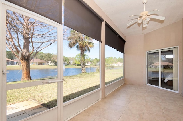 unfurnished sunroom featuring a ceiling fan and a water view