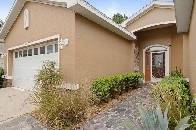 8231 SW 79th Ct, Ocala, FL 34476 - view of exterior entry with stucco siding, driveway, and an attached garage