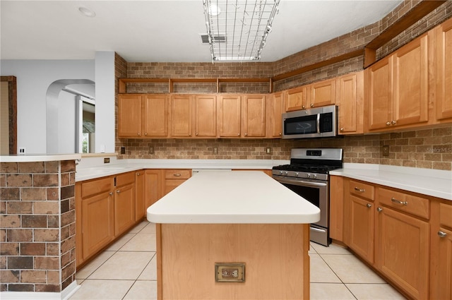 8231 SW 79th Ct, Ocala, FL 34476 - kitchen featuring tasteful backsplash, appliances with stainless steel finishes, light countertops, a center island, and light tile patterned flooring