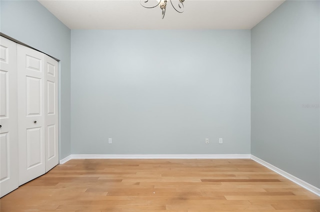 8231 SW 79th Ct, Ocala, FL 34476 - unfurnished bedroom featuring light wood finished floors, a closet, a notable chandelier, and baseboards