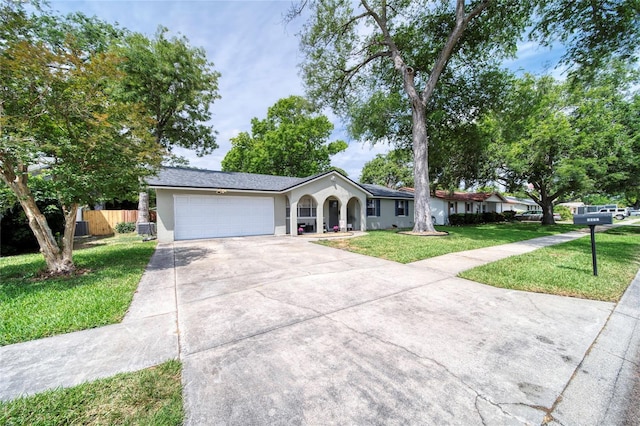 ranch-style home with a front yard, stucco siding, concrete driveway, an attached garage, and fence