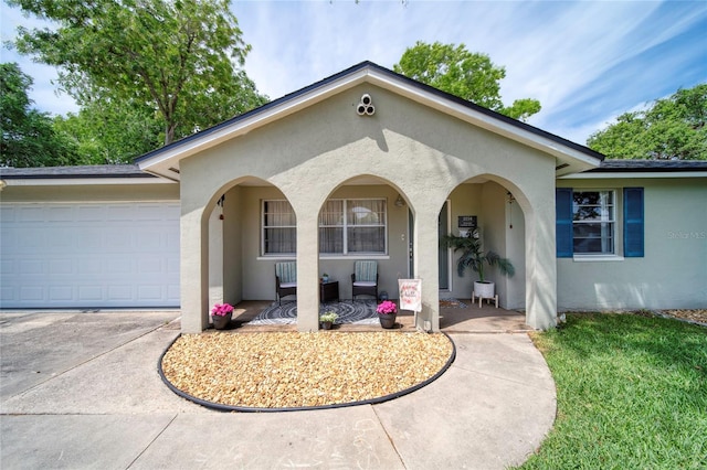 view of front of house with stucco siding, covered porch, concrete driveway, and a garage