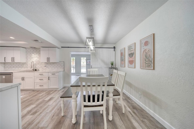 dining room featuring light wood finished floors, a textured ceiling, and a textured wall